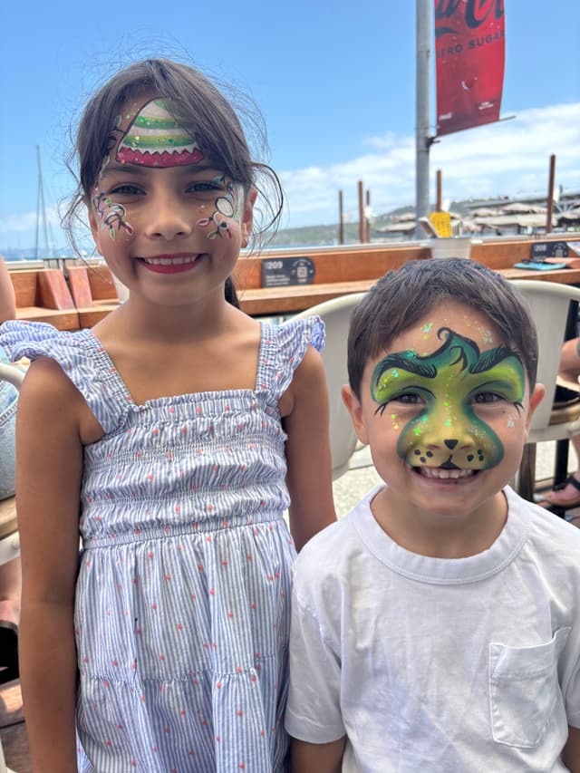 Two kids with colourful face paint at the waterfront